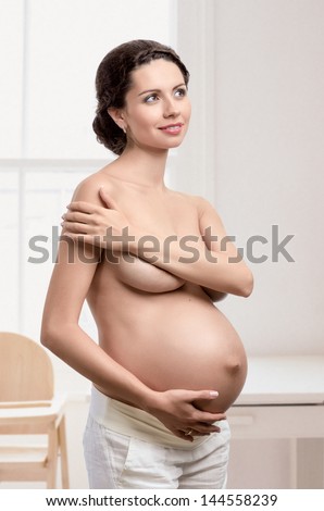 Beautiful figure of young pregnant woman at home
