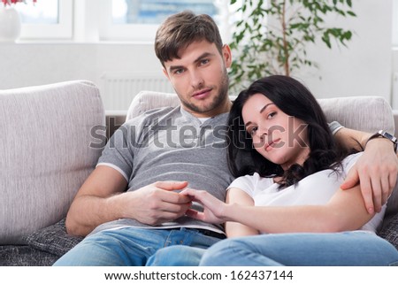 young couple are sitting down on a couch embracing each other