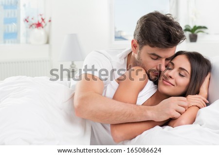 Young Adult Heterosexual Couple Lying On Bed In Bedroom
