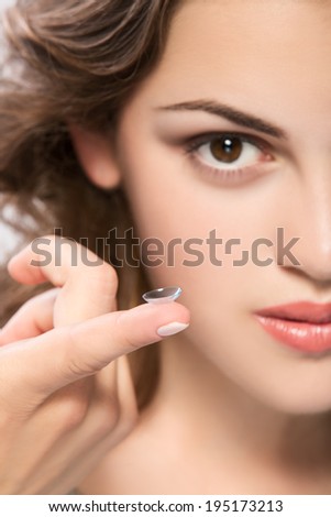 contact lens on finger of young woman looking on camera