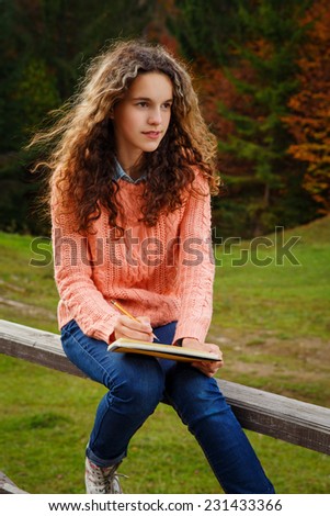 Young artist with sketch in note at autumn landscape