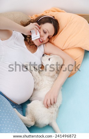 Pregnant woman speaking on phone with her dog