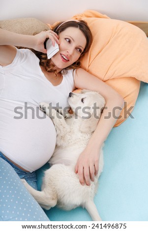 Pregnant woman speaking on phone with her dog