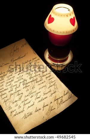 Old love letter and romantic candle burning on a black background