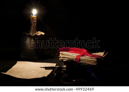 Old love letter, antique quill, stack of letters tied with a red ribbon and candle
