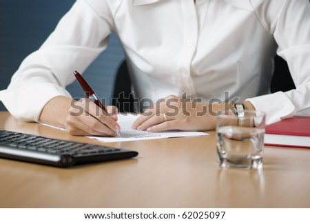 Businesswoman seating at the desk in office signing documents