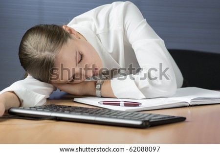 Tired businesswoman sleeping at her desk in office