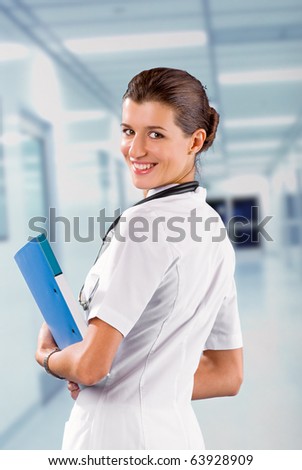 young  brunette in white medical gown and a stethoscope and file folder in an hospital