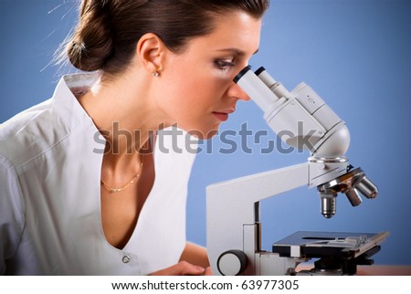 Young female doctor working with a microscope in a laboratory; blue background