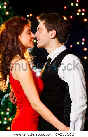 Young happy loving couple dancing at Christmas celebration near New Year\'s tree