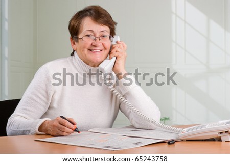 Mature businesswoman job searching in newspaper and speaking on phone