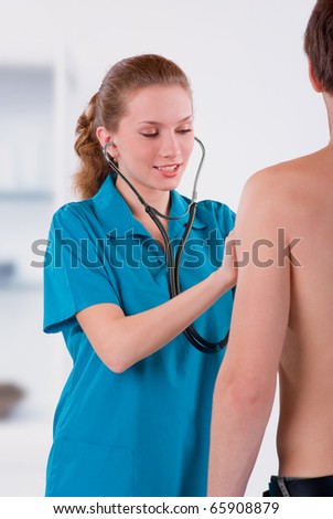 Female young Doctor listening to heartbeat of young man in office