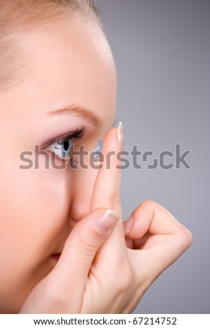 Young woman Inserting a contact lens closeup