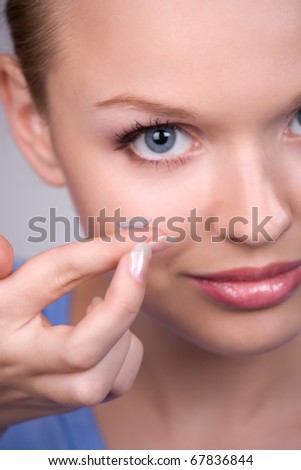 contact lens on finger of young woman looking on camera