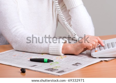 hands of an elderly woman calling on the phone by newspaper ad