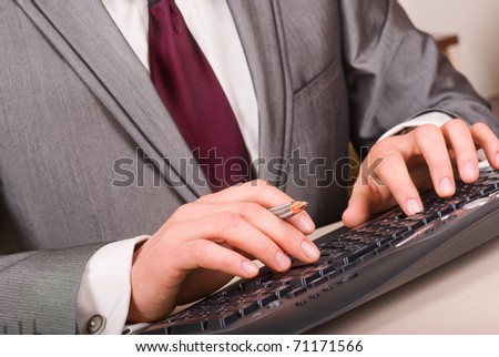 Close-up of businessman hands with pen typing on black computer keyboard