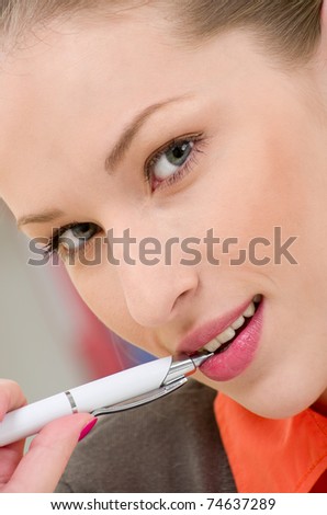 portrait of young businesswoman holding pen in mouth looking in camera