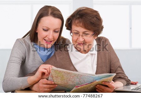 senior woman with her daughter reading map and choosing vacation