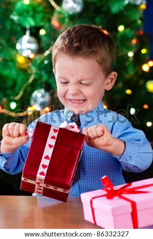excitement little boy opening Christmas gift near New Year\'s tree