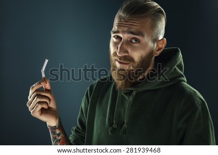 Close up portrait of young attractive man breaking down cigarette to pieces. Studio shot