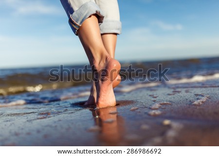 feet of woman  in the sea waves on sunset