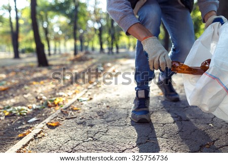 young man picking up trash outdoor. close up