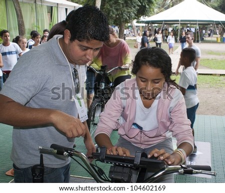 RIO DE JANEIRO - JUNE 04: staff member and unidentified girl adjusts monitor of the bicycle during  the Event Green Nation Fest.  Event Green Nation Fest,June 04, 2012 in Rio de Janeiro, Brazil
