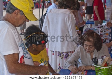 RIO DE JANEIRO - AUG 18: unidentified man and girl look the japanese lady write in a paper ribbon at the japanese party in Rio de Janeiro. August 18, 2012 in Rio de Janeiro, Brazil