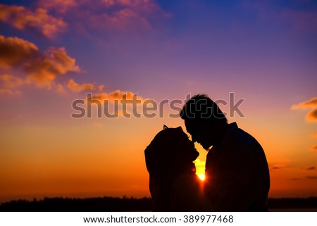 Silhouette of couple holding hands in heart shape with sunset in the middle. Vintage, retro toned photo.