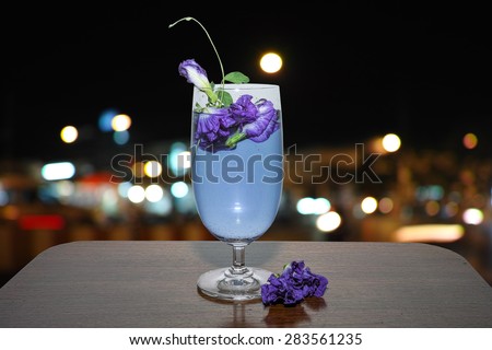 A defocus night city background of a glass of Aunchun juice put on a wooden table.