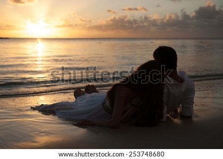 Romantic couple enjoying a beach walk at sunset. Happy Romantic Couple Enjoying Beautiful Sunset at the Beach.