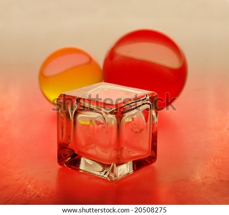 A still-life from three objects of a glass cube and two glass spheres, light with filters of red and yellow colour