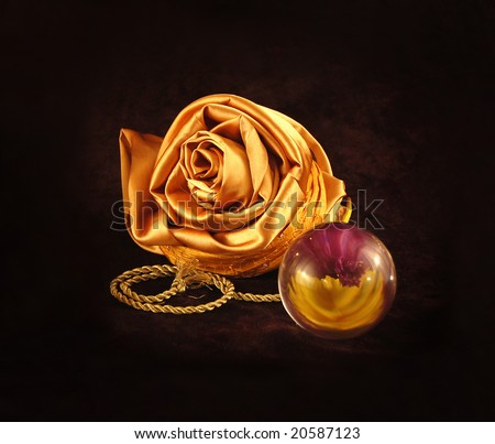 The still-life from gold things, a flower made of a shirt, and a glass sphere in which is reflected a flower