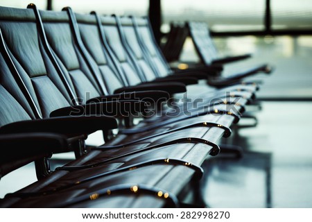 Row of leather chairs at international airport terminal background.