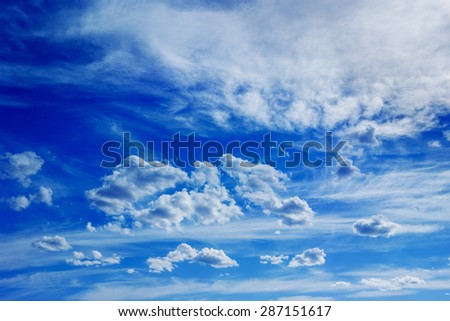 Horizontal image of white fluffy clouds on blue spring sky background.