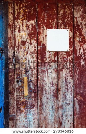 Closeup image of red wooden rusty door with white blank plate. Background for advertising.