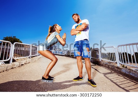 Young attractive girl is asking her man for forgiving making common gesture at summer bright background.