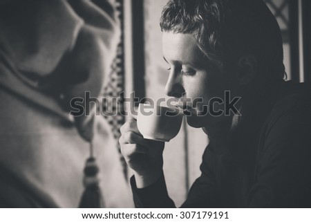 Closeup black and white portrait of man drinking coffee in vintage style.
