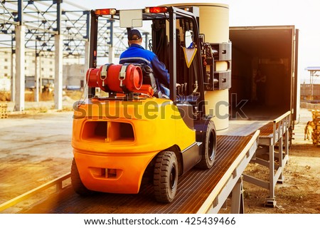 Forklift is putting cargo from warehouse to truck outdoors