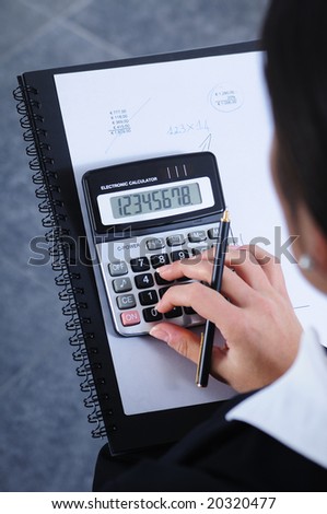 businesswoman write and calculate in office; calculator and pen