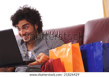 a young man  using his credit card to purchase over the internet, happiness and amazement
