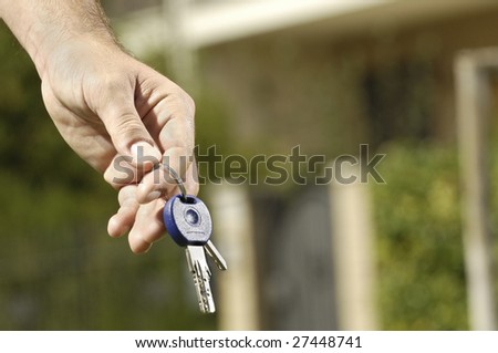 young man and new home; young man looking new home with door key in hand; concept of real estate