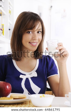 young woman drinking milk on the white background, smiling and looking in camera