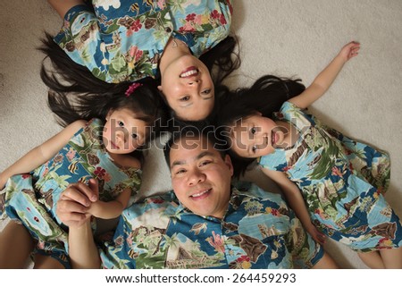 Asian family wearing Hawaiian shirts laying on floor smiling
