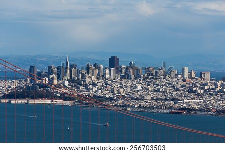 View on Golden Gate bridge and San Francisco downtown looking south with blue water and sky partially obscured by clouds
