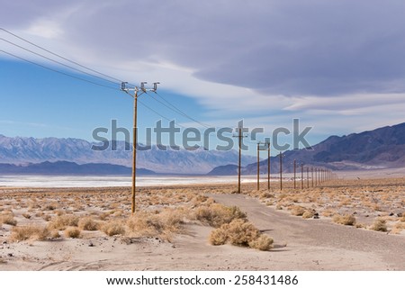 Power lines in Mojave desert next to saline Owens lake with Sierra Nevada mountains on background