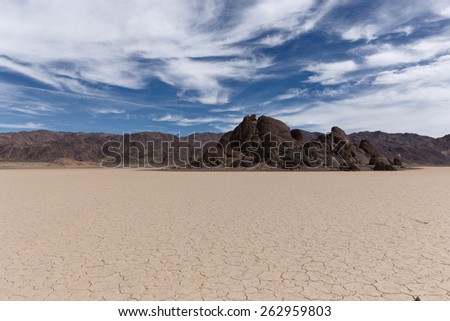 Dry lake bed with cracked mud on a lake floor, blue sky, clouds and mountains. Racetrack Playa. Death Valley national park. California. USA.