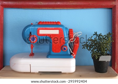 Toy and vintage sewing machine on blue background with pot of plant