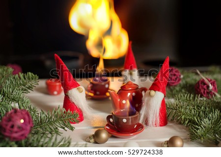 Santa\'s helpers sitting near fireplace with xmas decorations and drinking hot tea. Christmas fairy tail. Christmas still life.