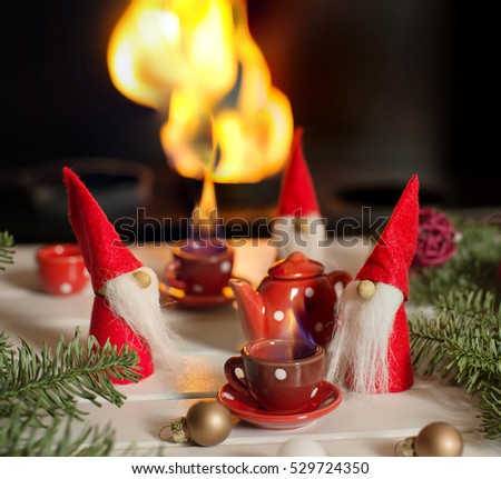 Santa\'s helpers sitting near fireplace with xmas decorations and drinking hot tea. Christmas fairy tail. Christmas still life.
